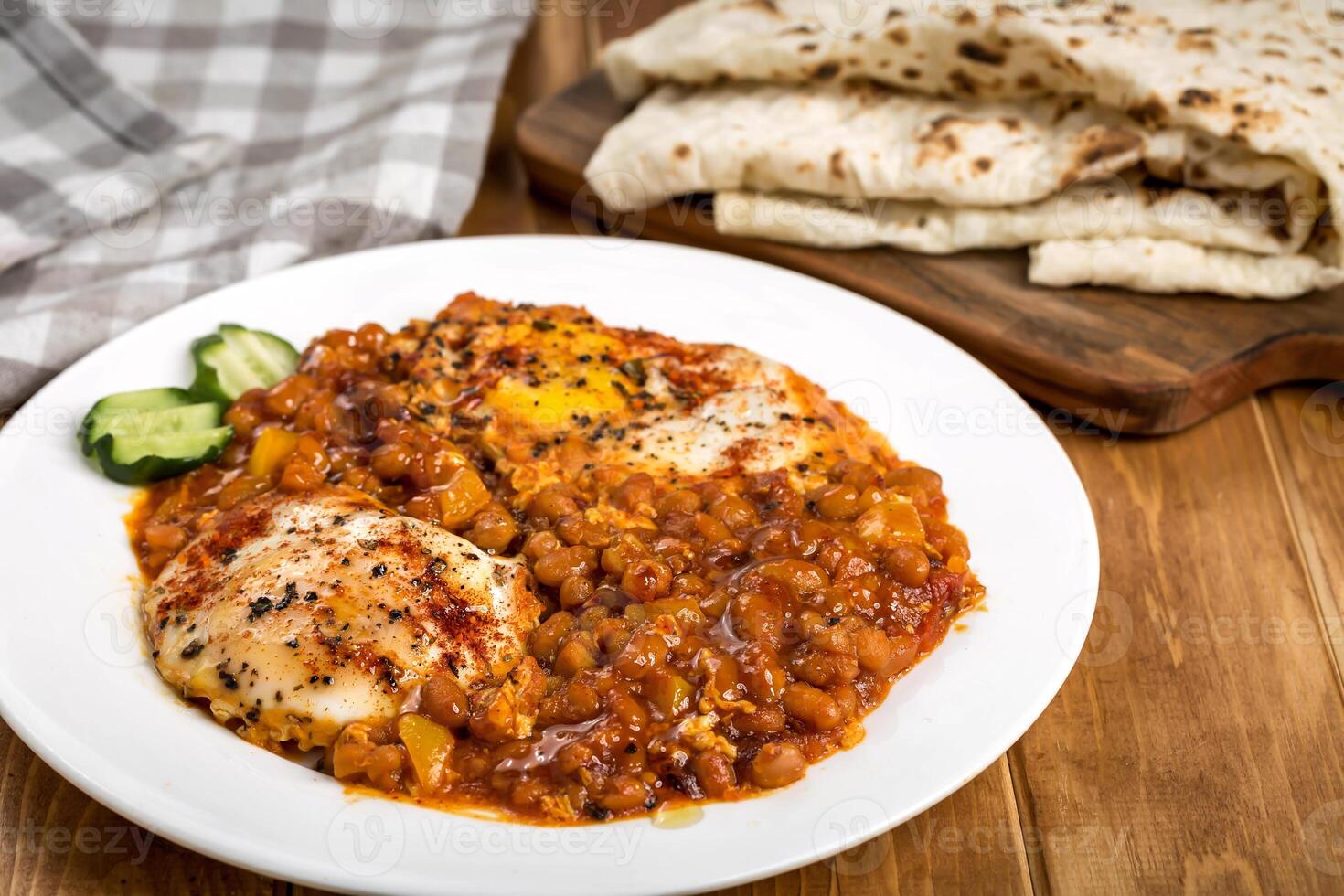 sunny side up egg with red beans and pita bread served in plate isolated on wooden table side view of arabic food photo