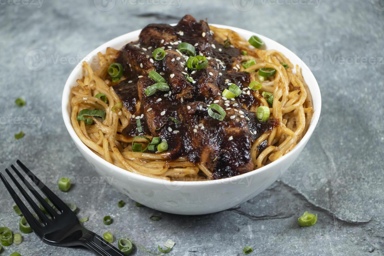 Teriyaki Grilled Chicken Noodles with green onion, and fork served in bowl isolated on grey background side view of asian food photo