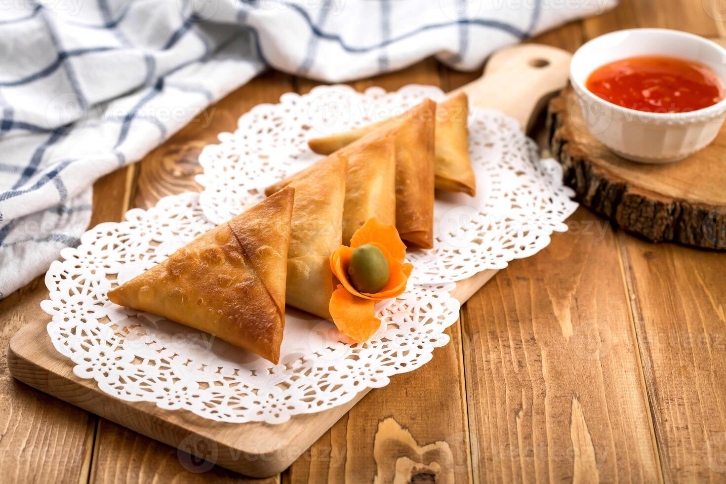 Samosa or Samboosa filled with vegetable and meat isolated on wooden board with tomato sauce on table side view of arabic ramadan food photo
