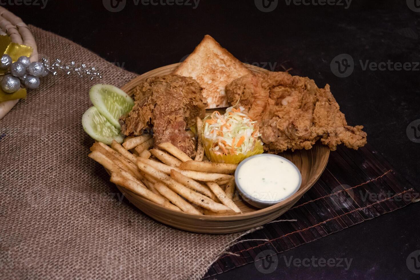broasted chicken with French Fries, Toasted Bread and Salad served in wooden plate isolated on dark background side view of bangladeshi fast food photo