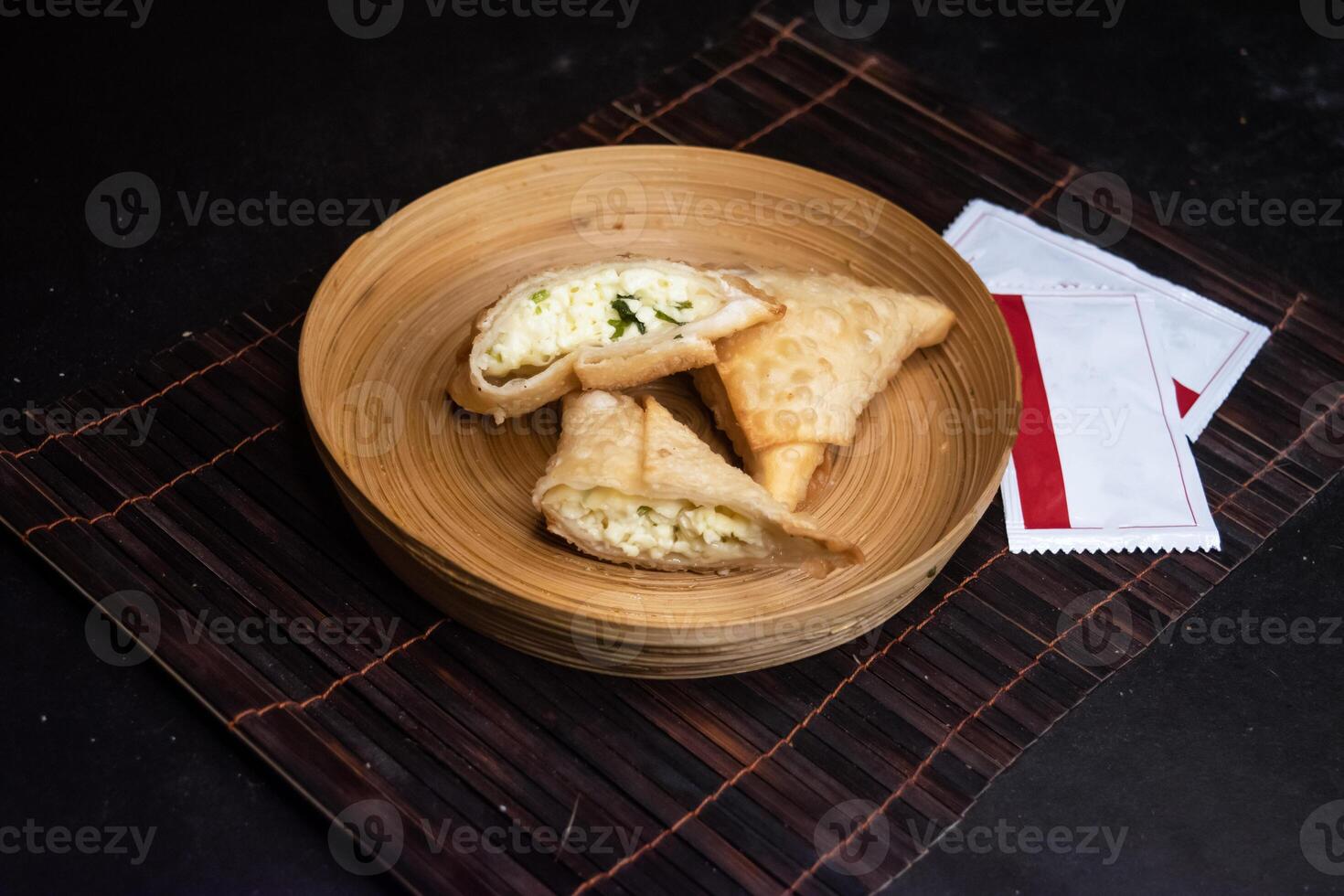 Cheese Samosa or Samucha with sauce served in wooden plate isolated on dark background side view of bangladeshi fast food photo