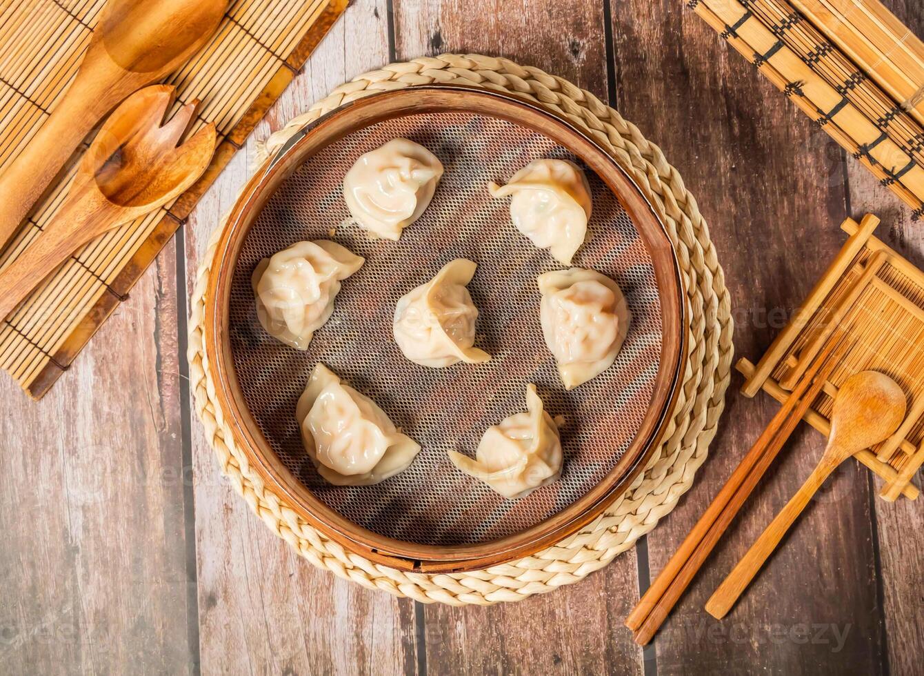 Steamed Shrimp Dumplings with chopsticks and spoon served in bamboo steamer isolated on wooden table top view of taiwan food photo