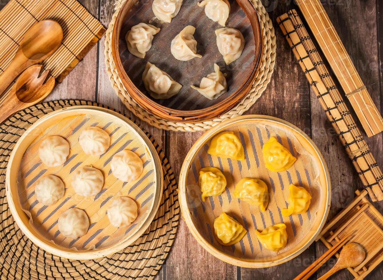 Assorted Steamed Shrimp Dumplings Verity with chopsticks and spoon served in bamboo steamer isolated on wooden table top view of taiwan food photo