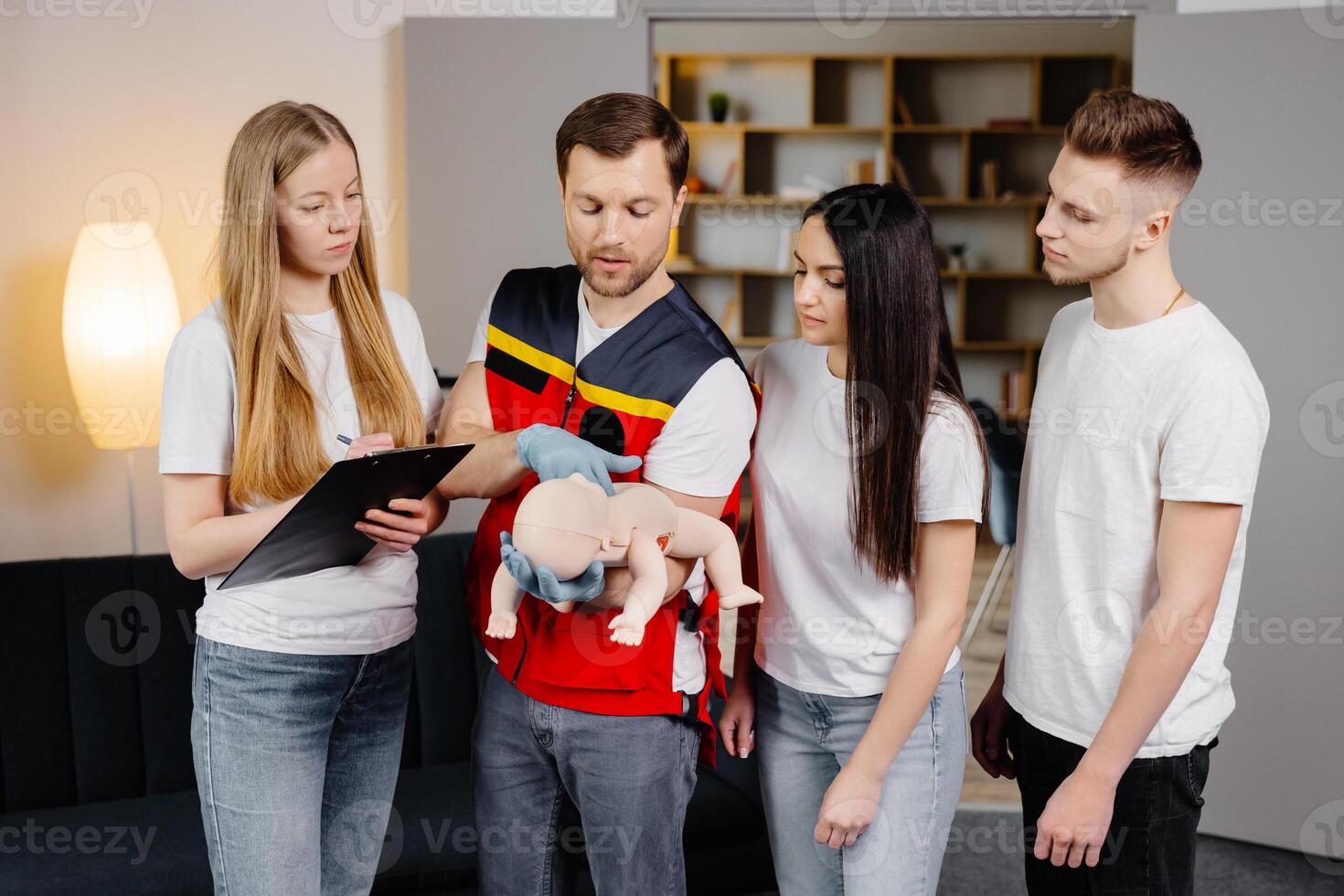 Group of people learning how to make first aid with dummy child during the training indoors photo