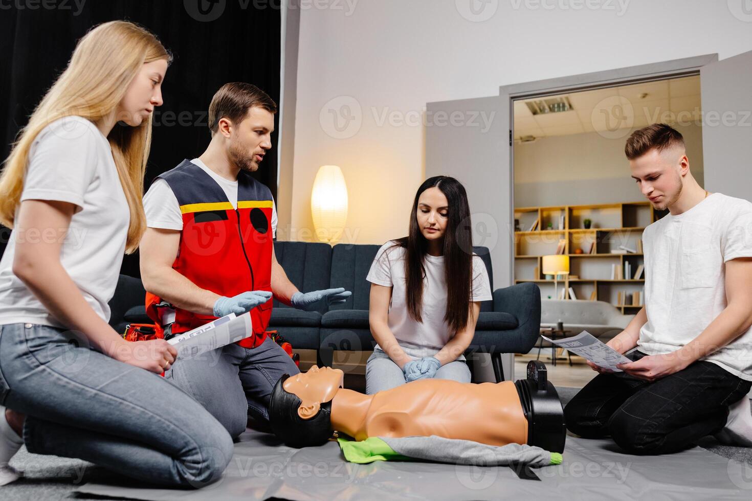 Group of people learning how to make first aid heart compressions with dummies during the training indoors photo