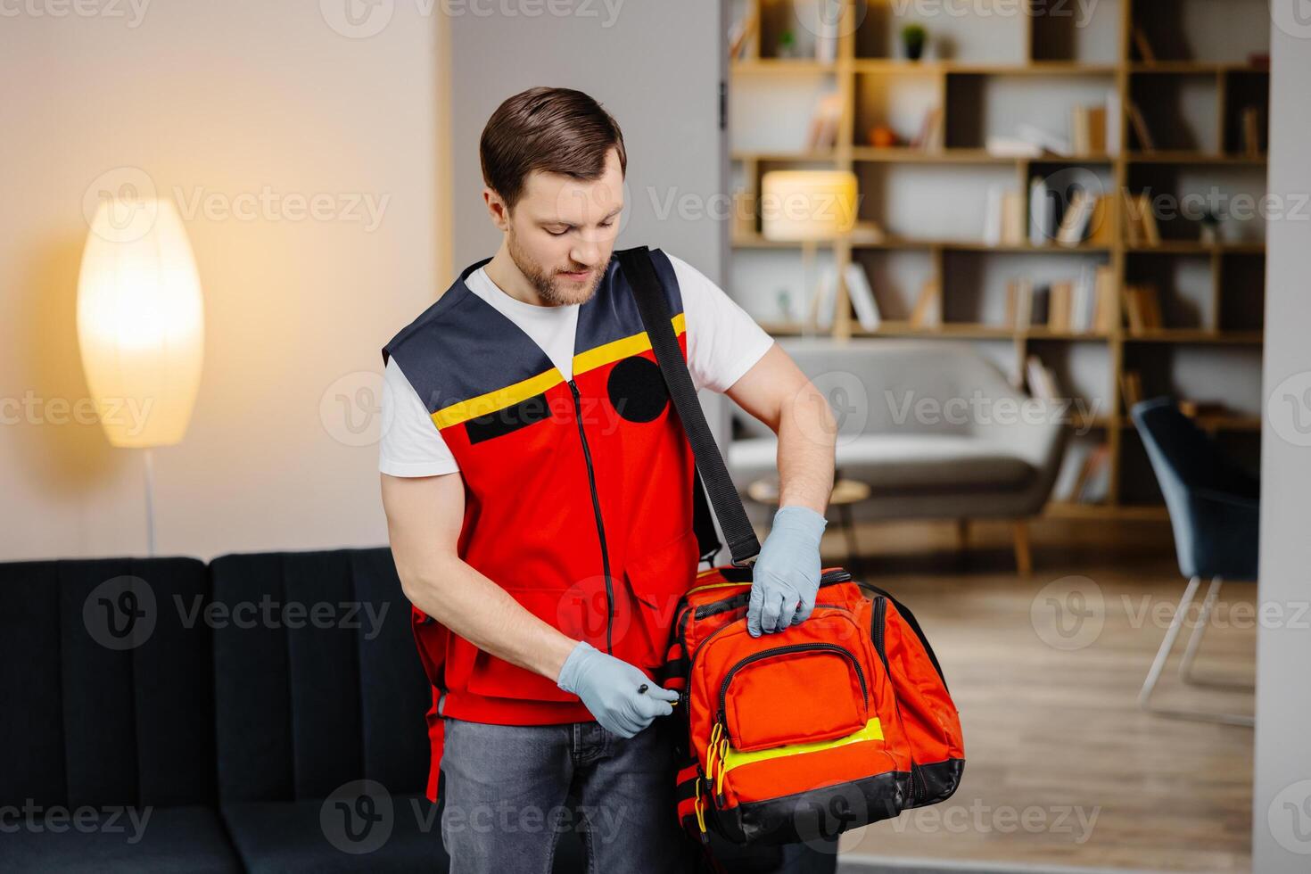 First aid course. A young male paramedic with a bag on his shoulders is standing in a classroom before a lecture photo