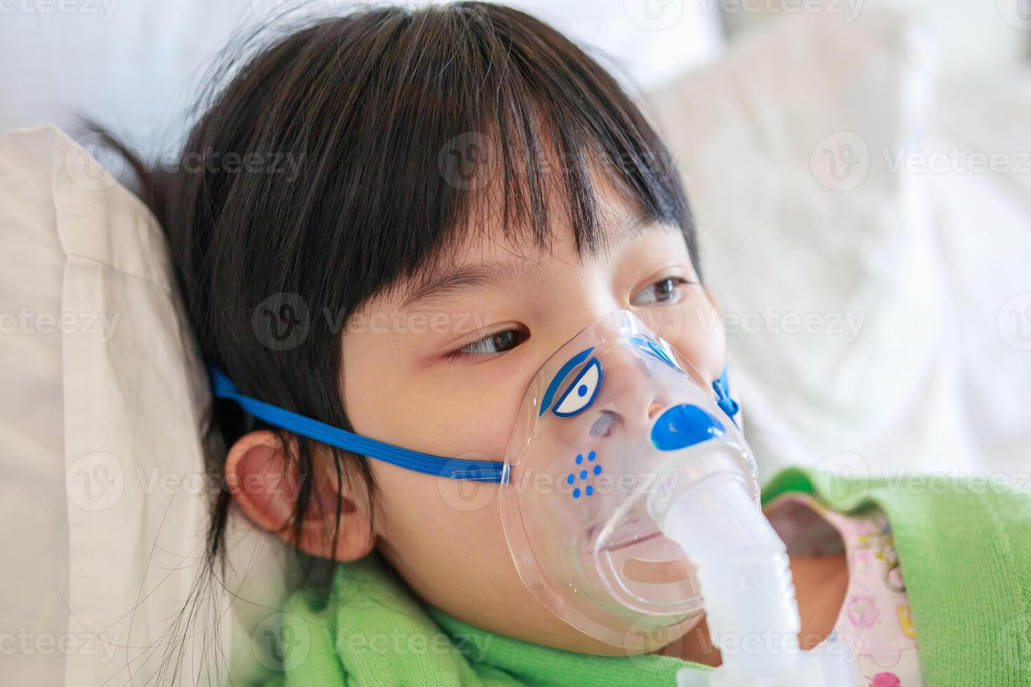 Sick little asian girl inhalation with nebulizer for respiratory treatment photo