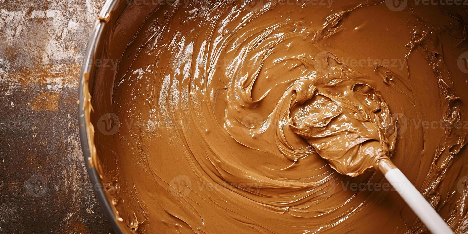 Peanut butter being stirred in large vat with paddle photo