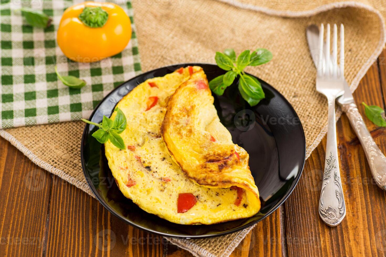fried omelette with sweet pepper and vegetables in a plate on a wooden table photo
