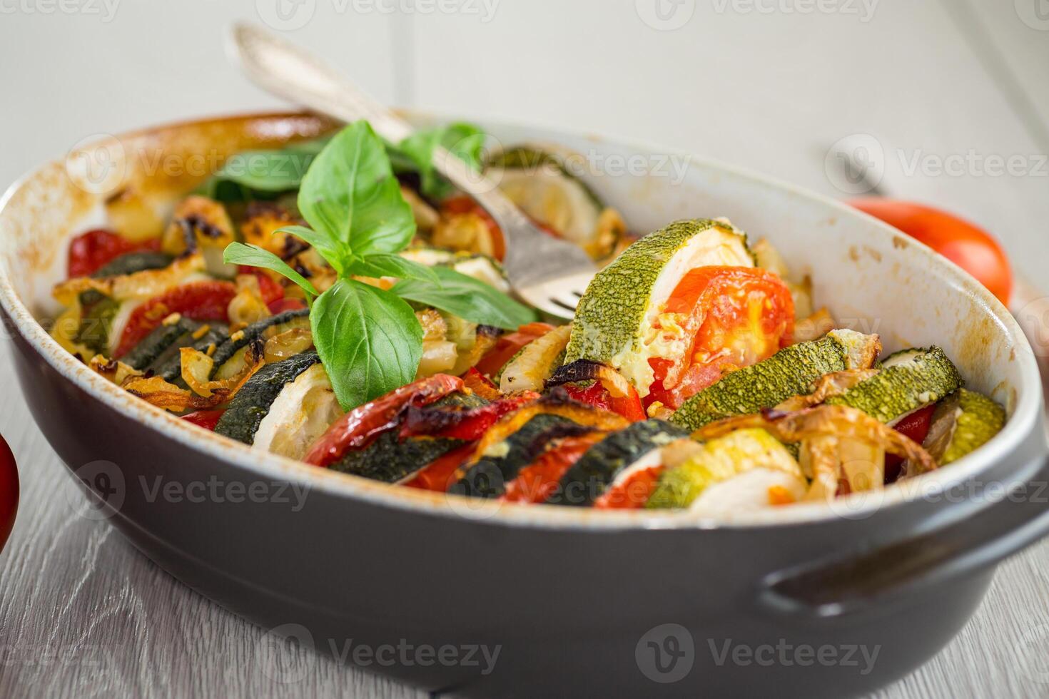prepared baked zucchini and tomatoes in circles in a ceramic form, vegetable snack photo