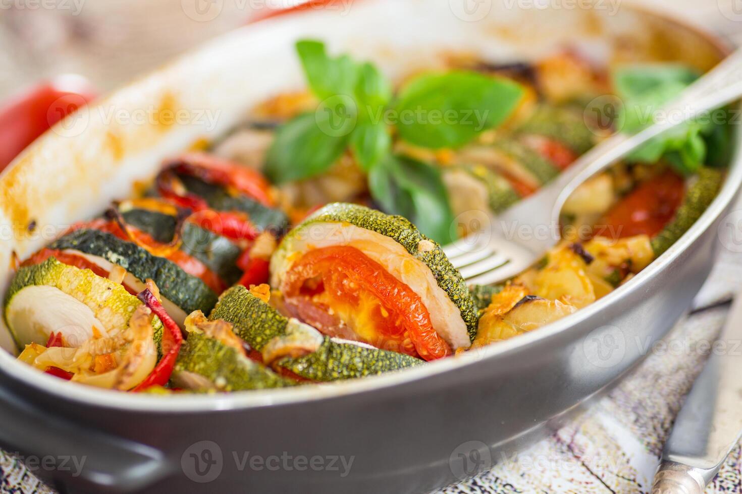 prepared baked zucchini and tomatoes in circles in a ceramic form, vegetable snack photo
