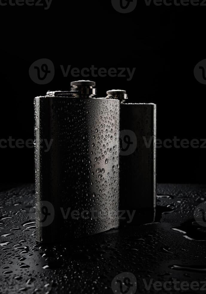 Stainless steel flasks on a black background with water drops. photo