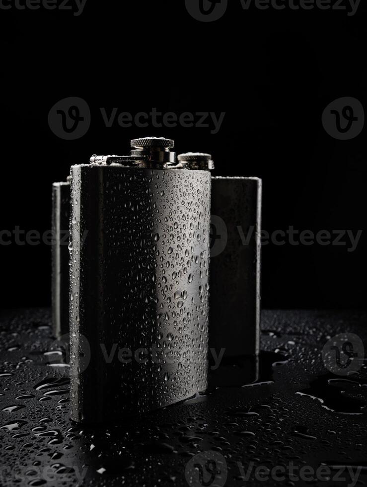 Stainless steel flasks on a black background with water drops. photo