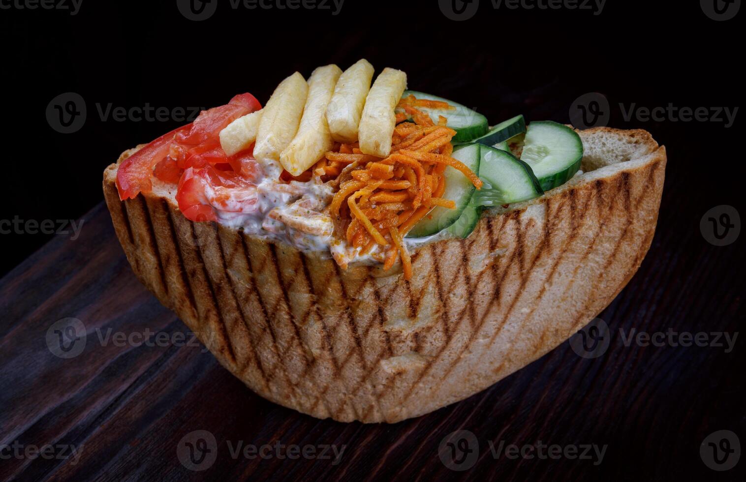 Doner with a crispy crust and delicious meat and vegetable filling on a dark background. photo
