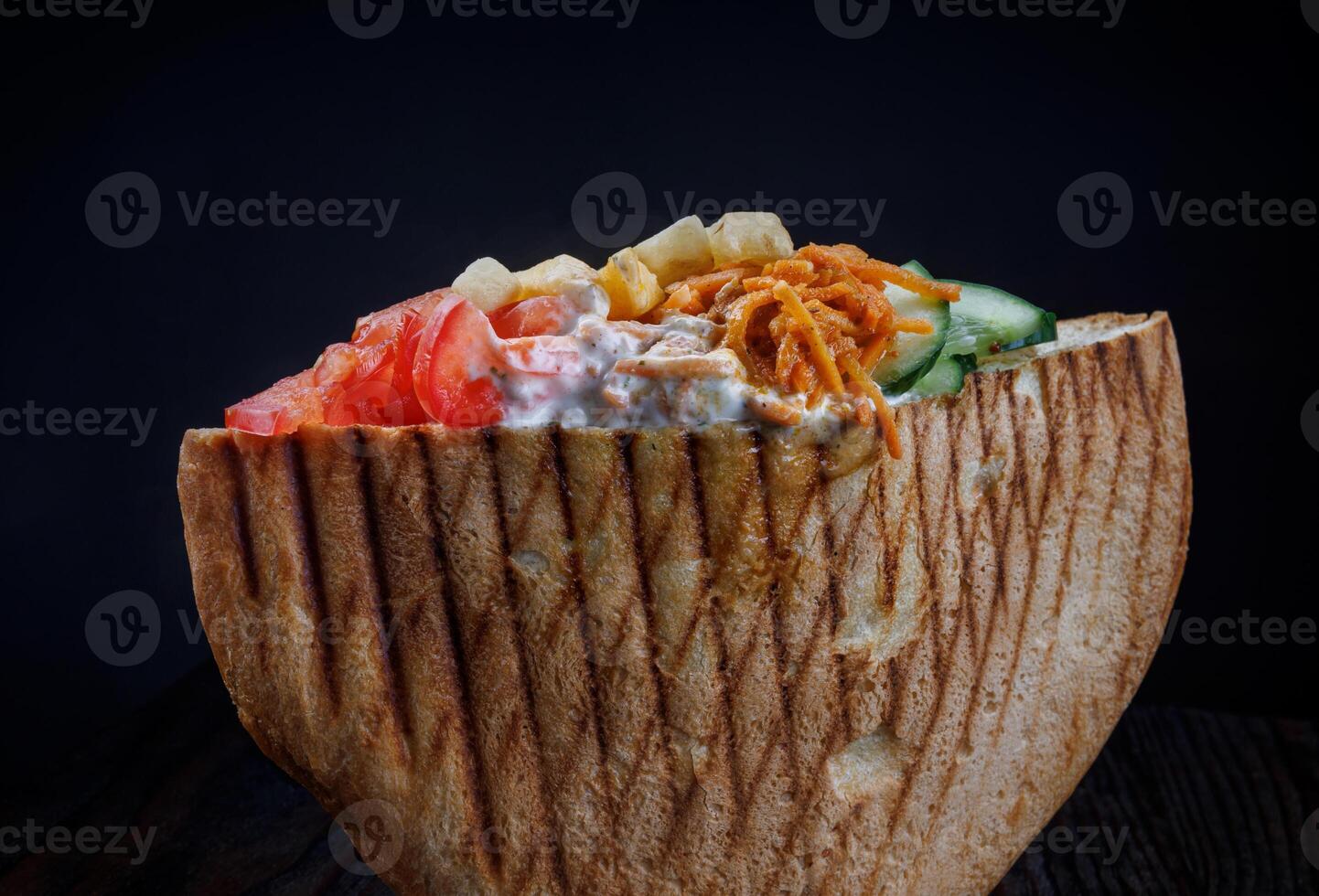 Doner with a crispy crust and delicious meat and vegetable filling on a dark background. photo