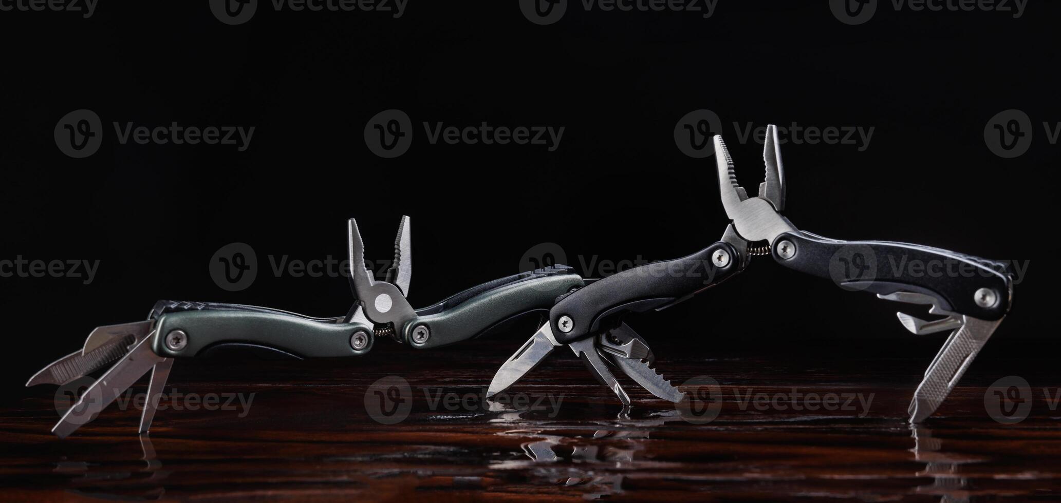 Steel open multitool on red background. Multitool with many useful tools. photo