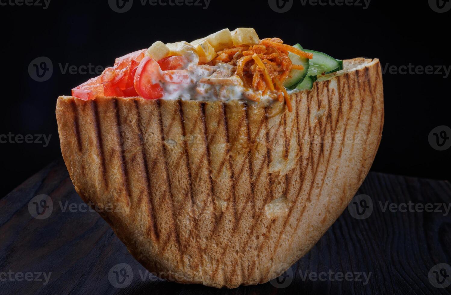 Doner with a crispy crust and delicious meat and vegetable filling on a dark background. photo