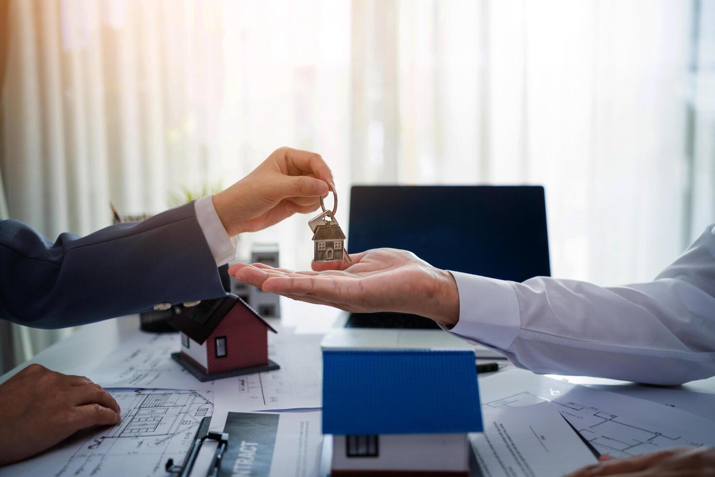 A man is handing a key to another man. The man holding the key is wearing a suit and tie. The other man is wearing a white shirt. Concept of professionalism and trust between the two men photo