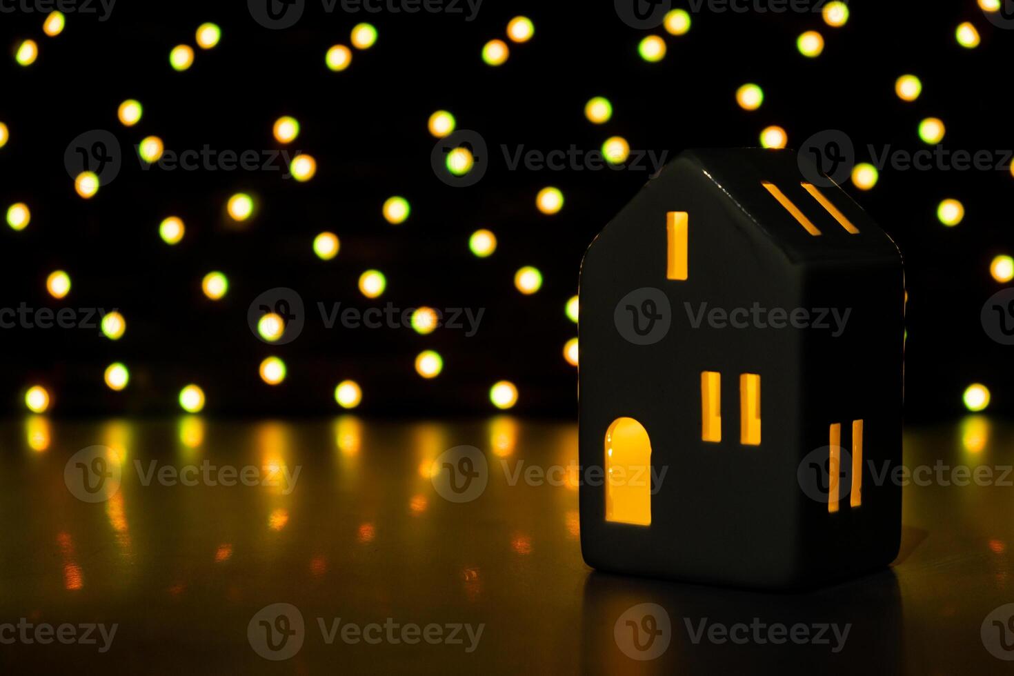 Christmas clay lantern house on dark bokeh light garland background. New year and Christmas preparation. Handmade eco-friendly decor. Sustainable Christmas decoration. Copy space photo