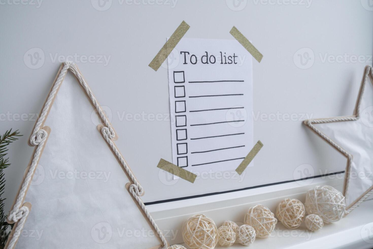 TO DO LIST checklist text on paper note stick on while wall with cozy minimalistic handmade Christmas decor. New year aims resolutions. Low key festive Planning and setting goals concept photo