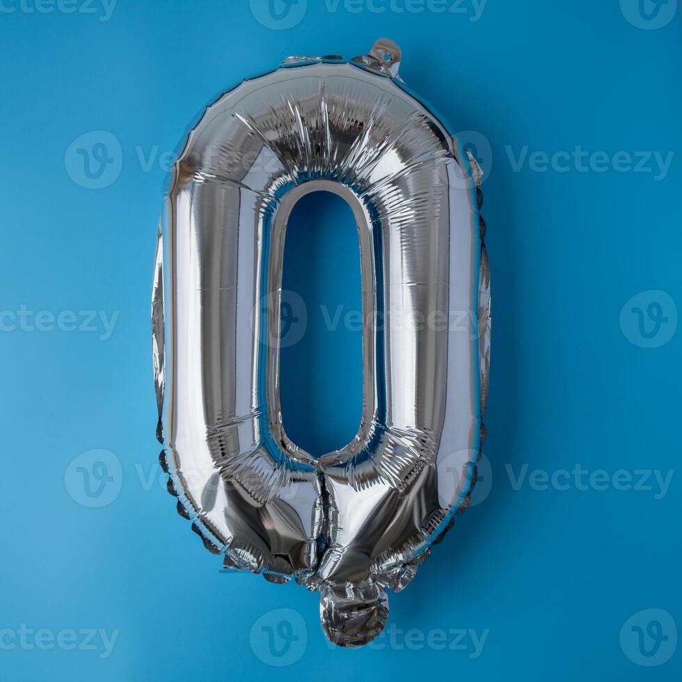 0 zero metallic balloon isolated on blue background. Greeting card silver foil balloon number Happy birthday holiday concept. Copy space for text. Celebration party congratulation decoration photo