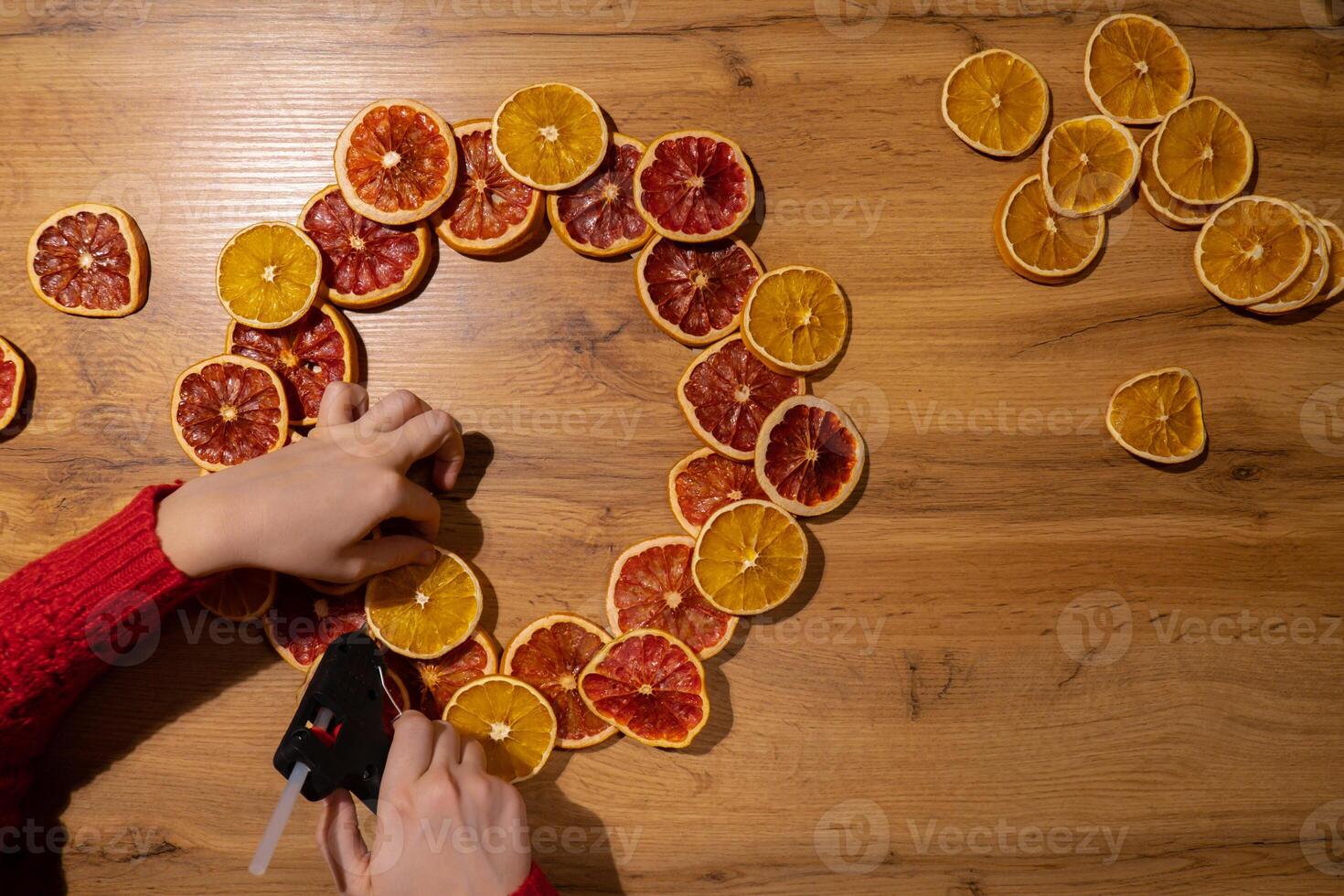 Step 2 Step by step instruction of making handmade Christmas wreath made of dry fruits oranges and grapefruits. Female hands creating craft homemade decor. New year celebration. Winter holidays photo