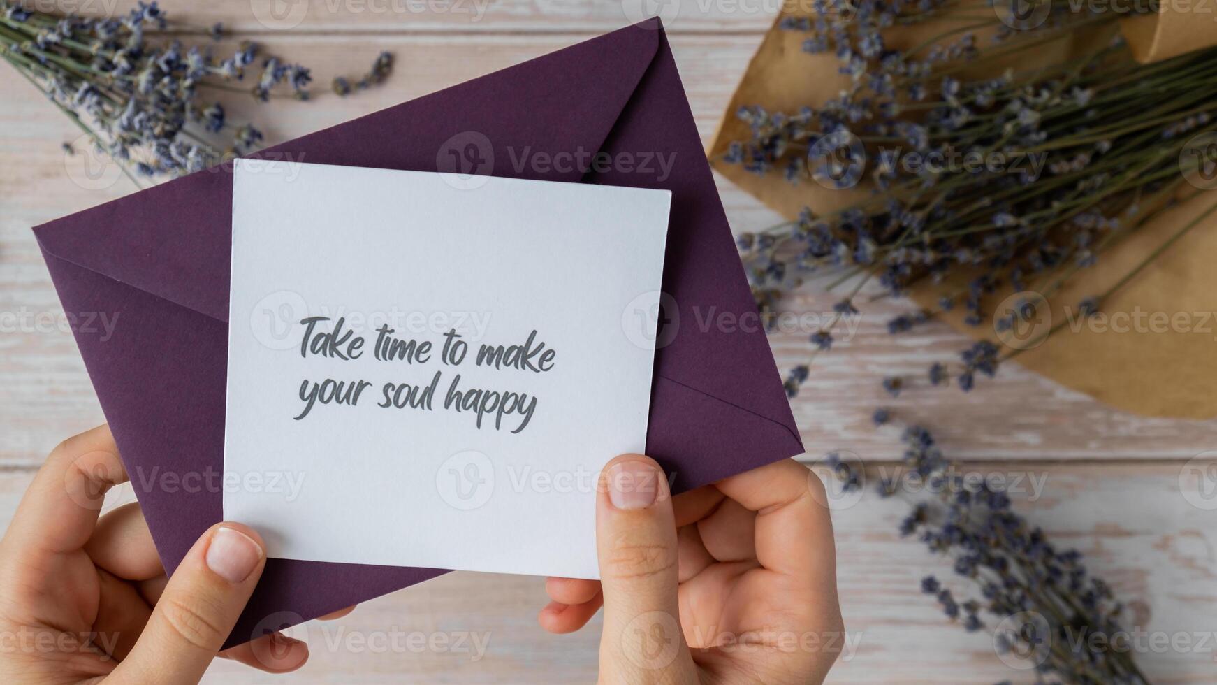 Female hands taking paper card note with text TAKE TIME TO MAKE YOUR SOUL HAPPY from violet envelope. Lavender flower. Top view, flat lay. Concept of mental spiritual health self care wellbeing mindfulness photo
