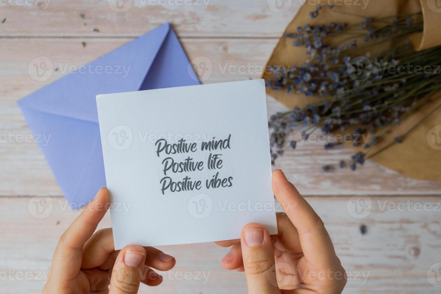 Female hands taking paper card note with text POSITIVE MIND LIFE VIBES from violet envelope. Lavender flower. Top view, flat lay. Concept of mental spiritual health self care wellbeing mindfulness photo
