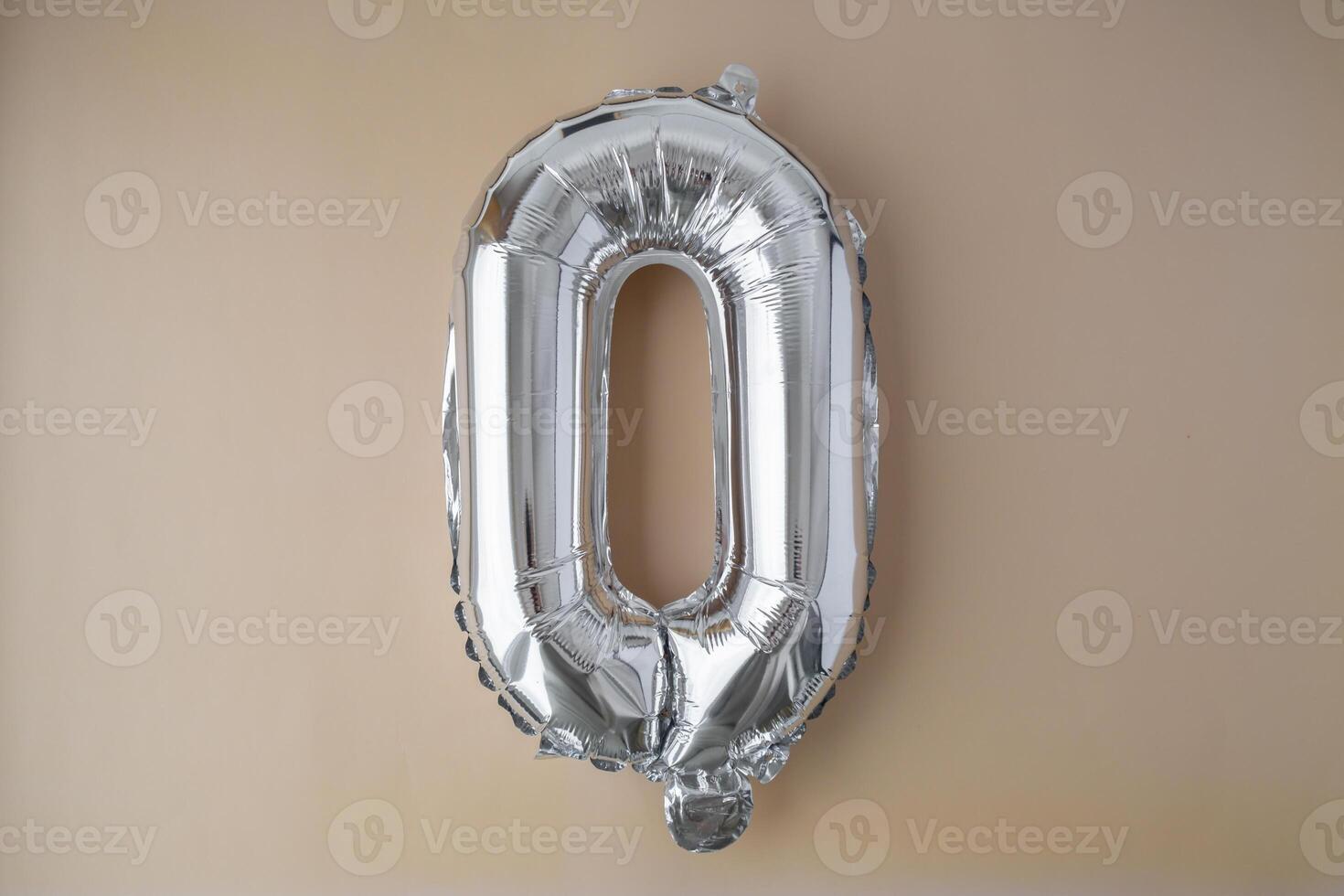 0 ZERO metallic balloon on beige neutral background. Greeting card silver foil balloon number Happy birthday holiday concept. Copy space for text. Celebration party congratulation decoration photo