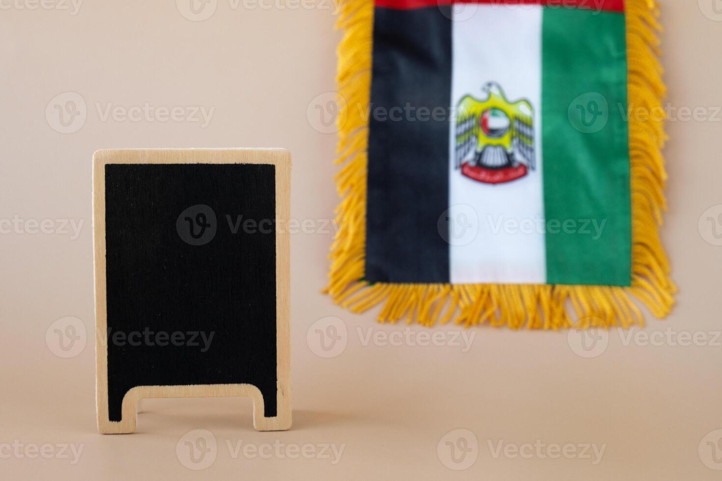 Empty blackboard template National symbol of UAE. United Arab Emirates small flag with Peregrine falcon on neutral beige background. Copy space for your text. Concept of National day Independence photo