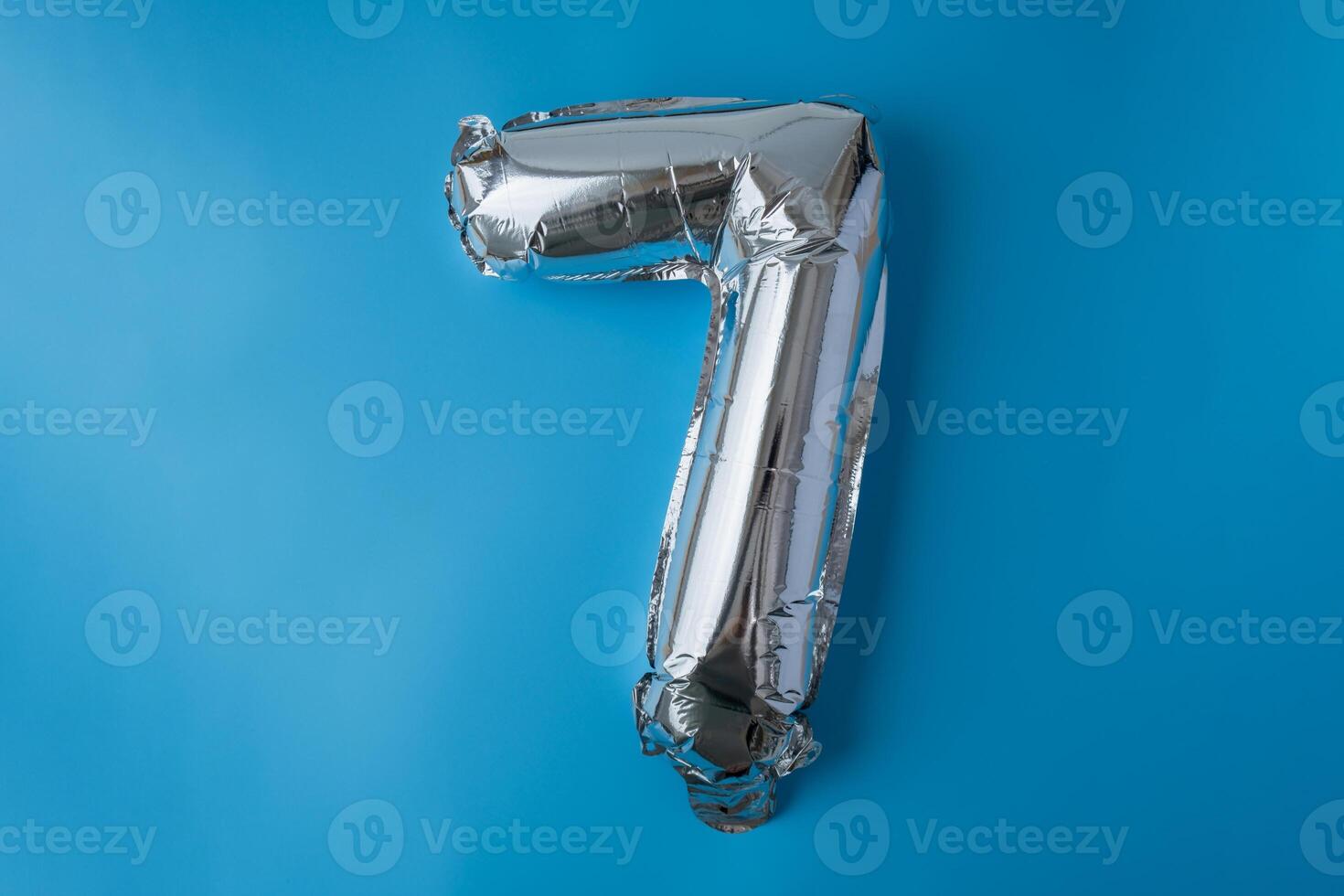 7 seven metallic balloon isolated on blue background. Greeting card silver foil balloon number Happy birthday holiday concept. Copy space for text. Celebration party congratulation decoration photo