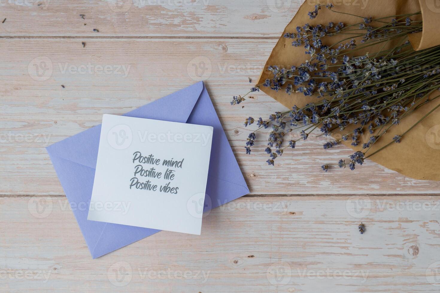 Female hands taking paper card note with text POSITIVE MIND LIFE VIBES from violet envelope. Lavender flower. Top view, flat lay. Concept of mental spiritual health self care wellbeing mindfulness photo