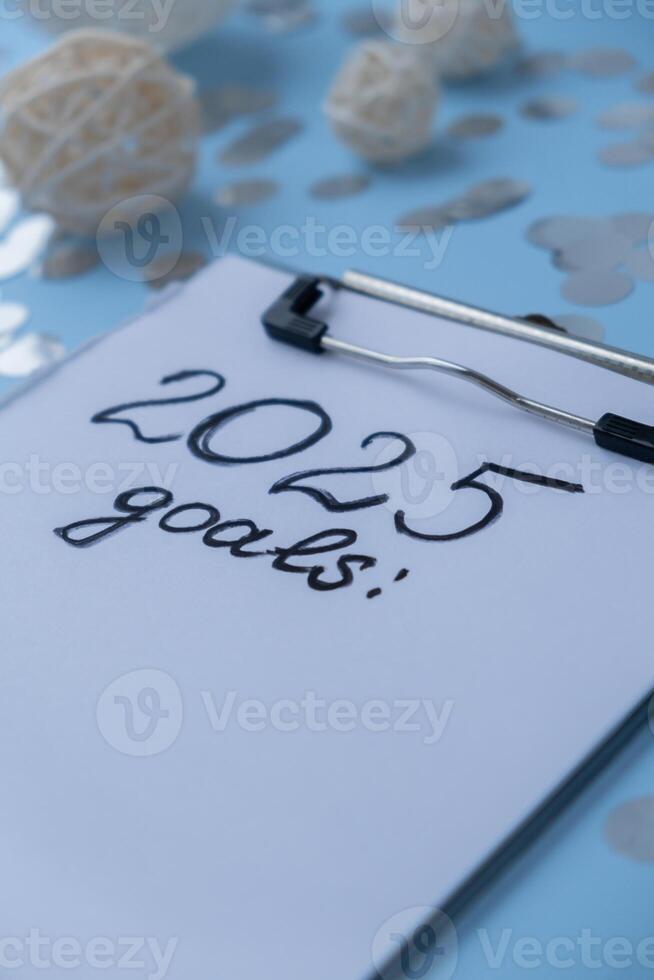 2025 GOALS New year's resolutions on paper note with Christmas decor. Making promises for new year, setting goals. Creating dream vision board motivation photo