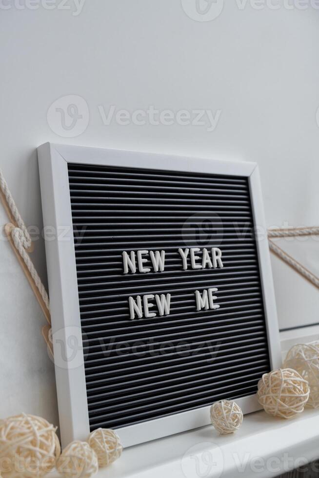 NEW YEAR NEW ME text on black letter board with cozy minimalistic handmade Christmas decor. New year aims resolutions. Low key festive Planning and setting goals concept photo