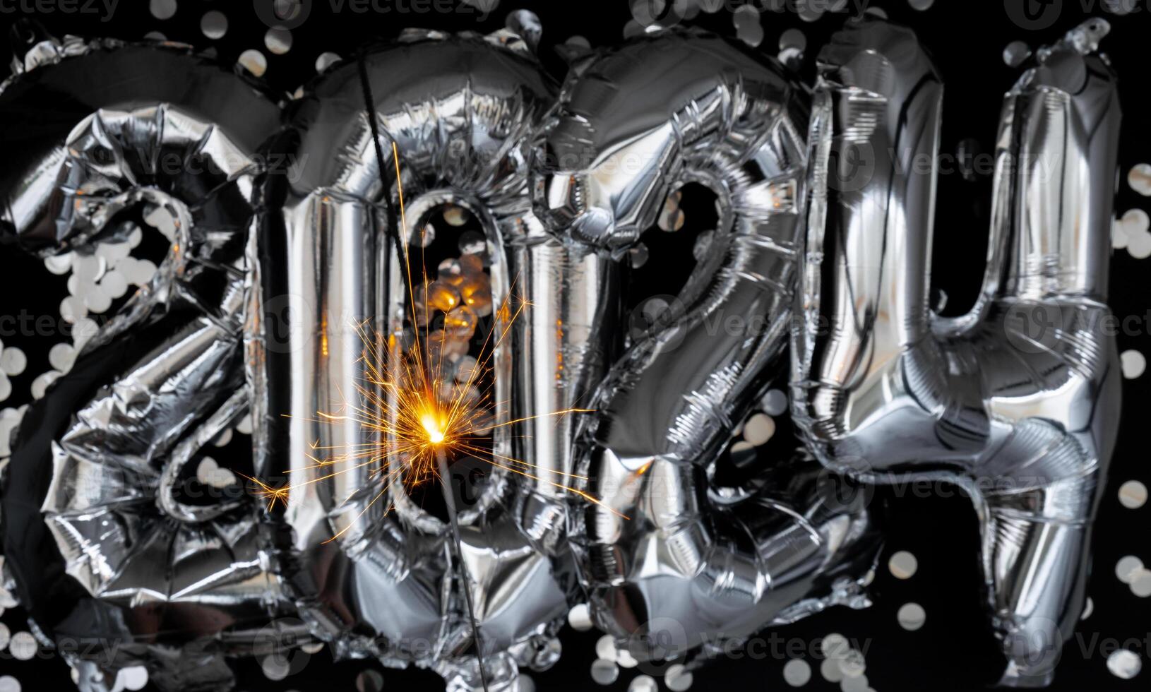 Happy new year 2024 metallic balloons with confetti and sparkler firework Bengal lights on dark black background. Greeting card silver foil balloons numbers Christmas holiday concept. Celebration party congratulation decoration photo