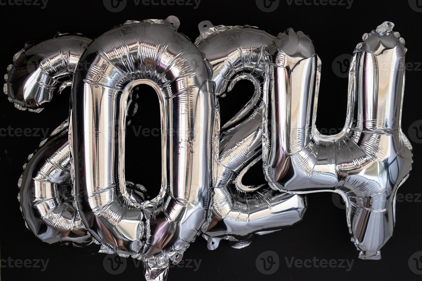 Happy new year 2024 metallic balloons with confetti on dark black background. Greeting card silver foil balloons numbers Christmas holiday concept. Celebration party congratulation decoration photo