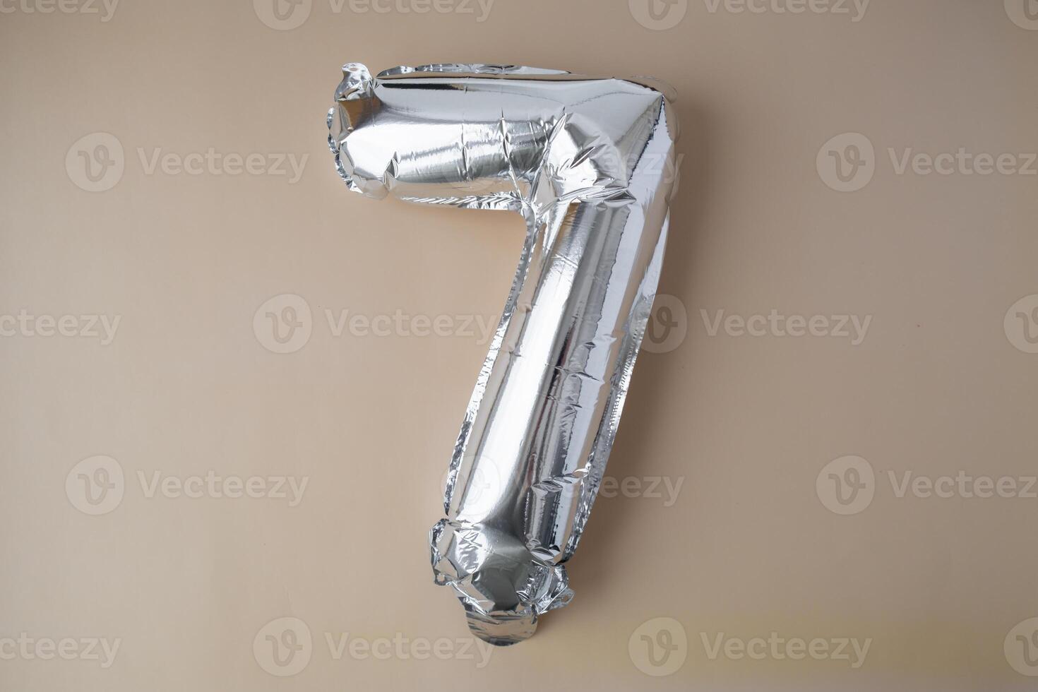 7 seven metallic balloon on beige neutral background. Greeting card silver foil balloon number Happy birthday holiday concept. Copy space for text. Celebration party congratulation decoration photo