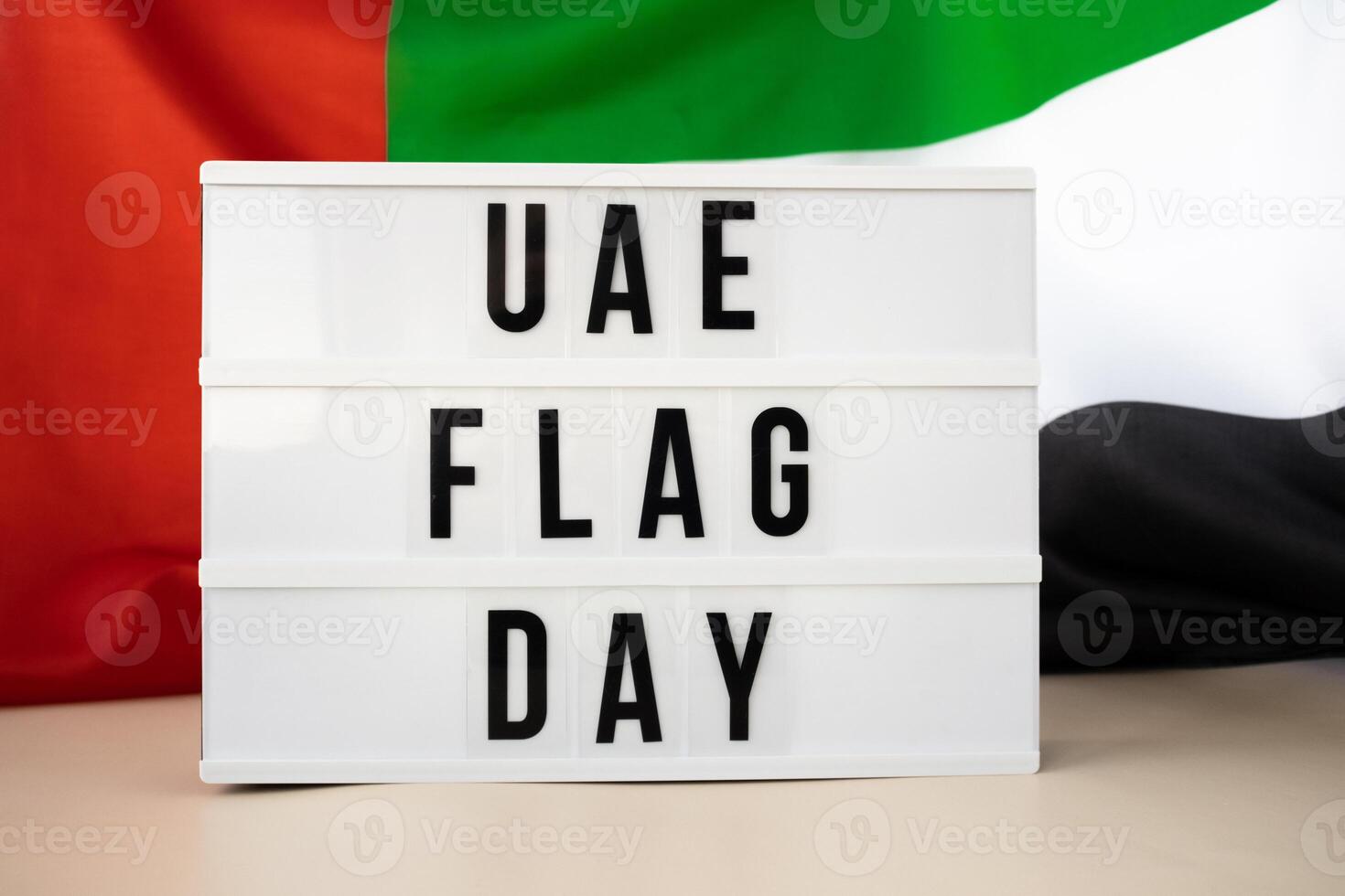 Lightbox with text UAE FLAG DAY on United Arab Emirates waving flag made from silk material. Independence Commemoration Day Muslim Public holiday celebration background. The National Flag of UAE. Patriotism photo