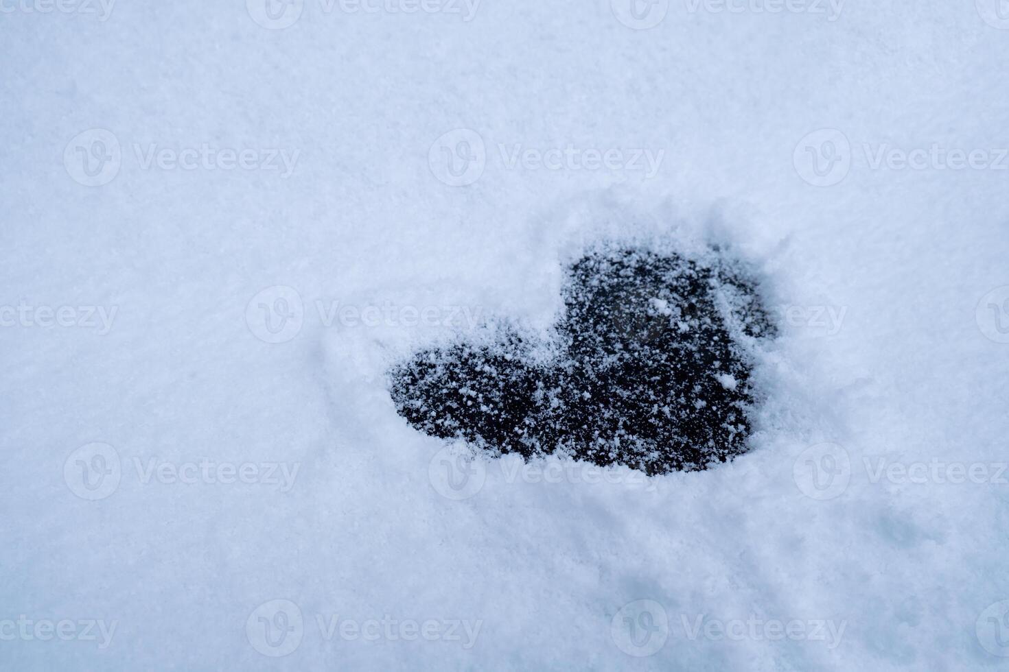Heart shape love sign is drawn in snowy glade romantic background. Valentine's Day cold heart in snow winter season weather. Outdoor concept photo