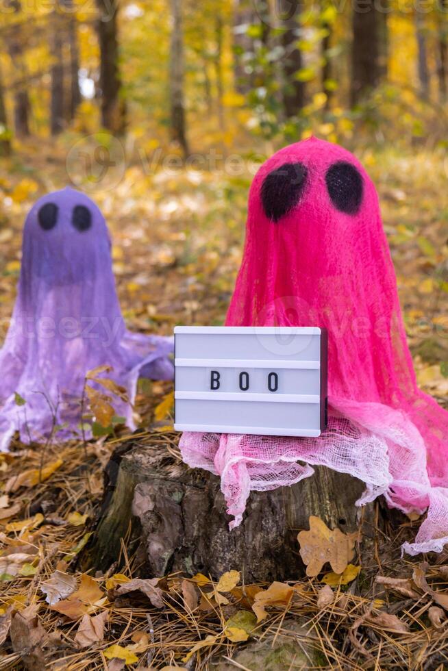 Lightbox BOO text Halloween holiday concept. Handmade colorful ghosts made from bandages and glue in autumn forest background. Children's art project. DIY concept. photo