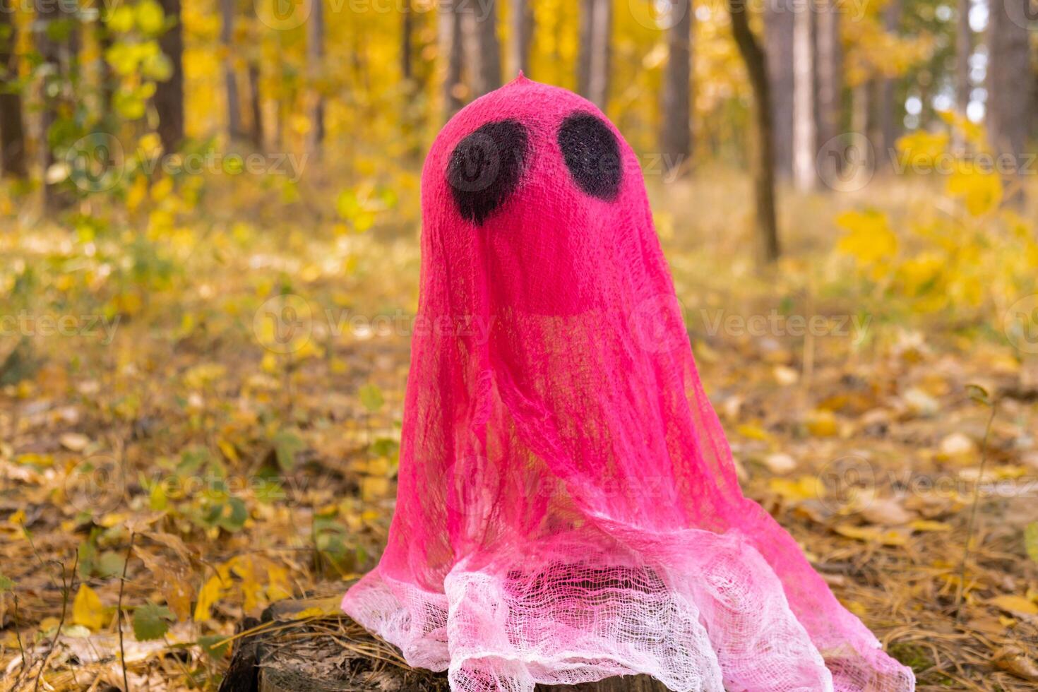 Creative handmade Halloween holiday decoration. pink ghost in autumn leaves forest. Zero waste homemade decor. Mystic place supernatural photo