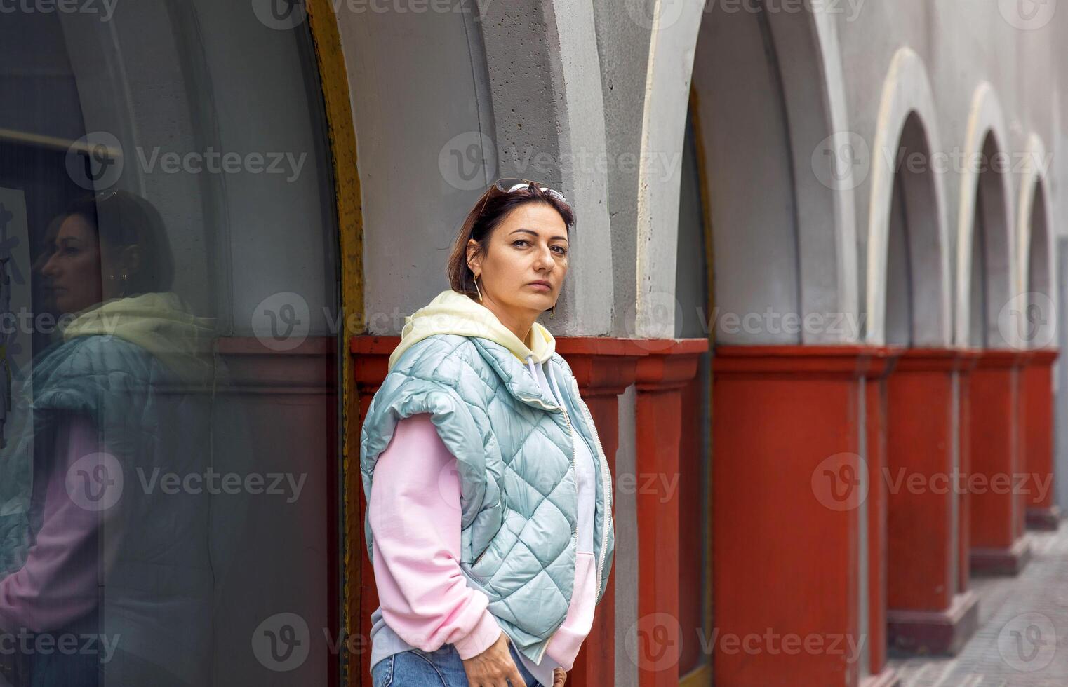 Confident woman in urban outfit posing against arched building background photo