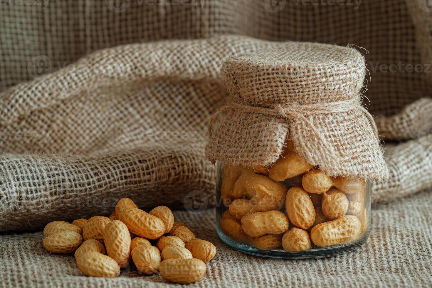 Peanuts in shell filling glass jar wrapped in burlap on rustic background photo