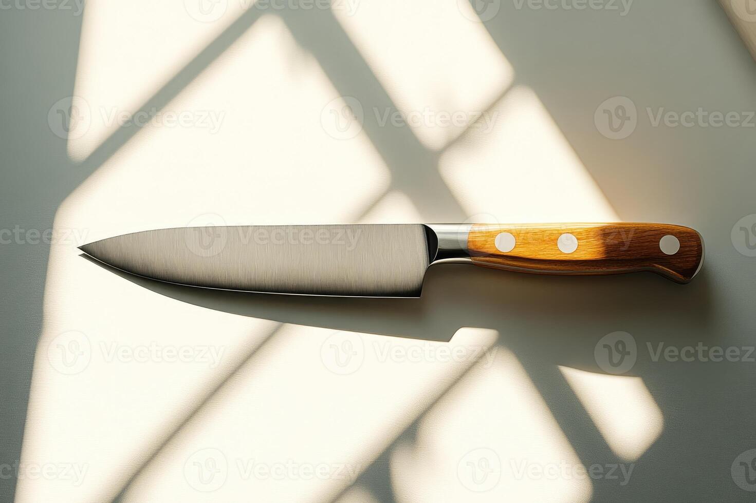 Large sharp kitchen knife lying on white table with window shadows photo