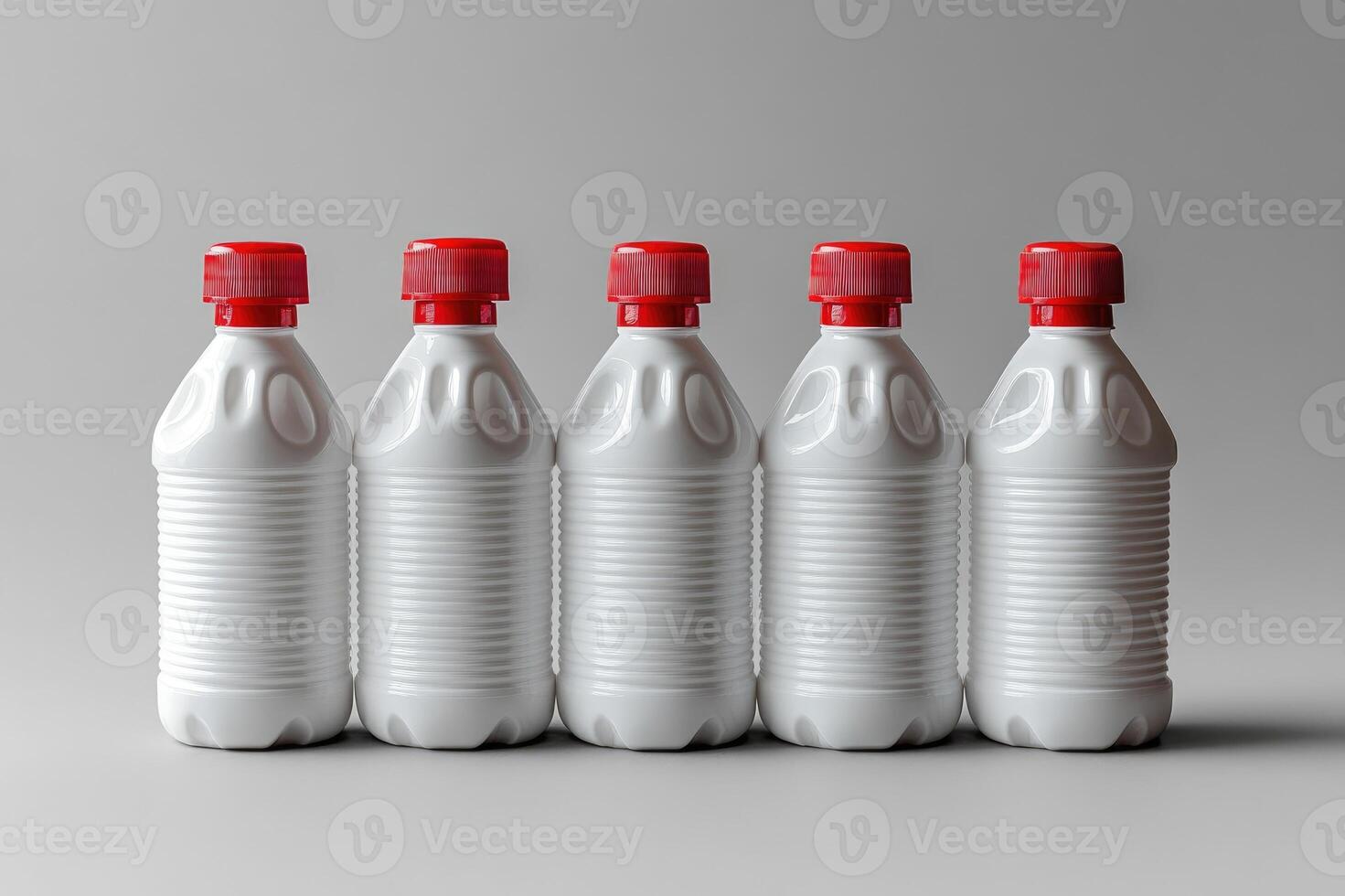 Row of white plastic bottles with red caps standing on gray background photo
