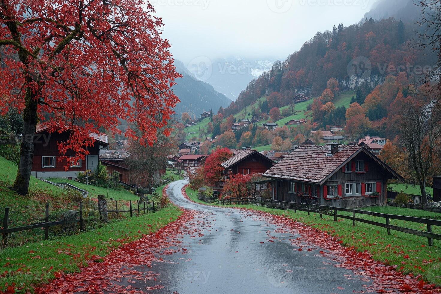 Wet asphalt road covered with red leaves leading to swiss chalets in autumn photo