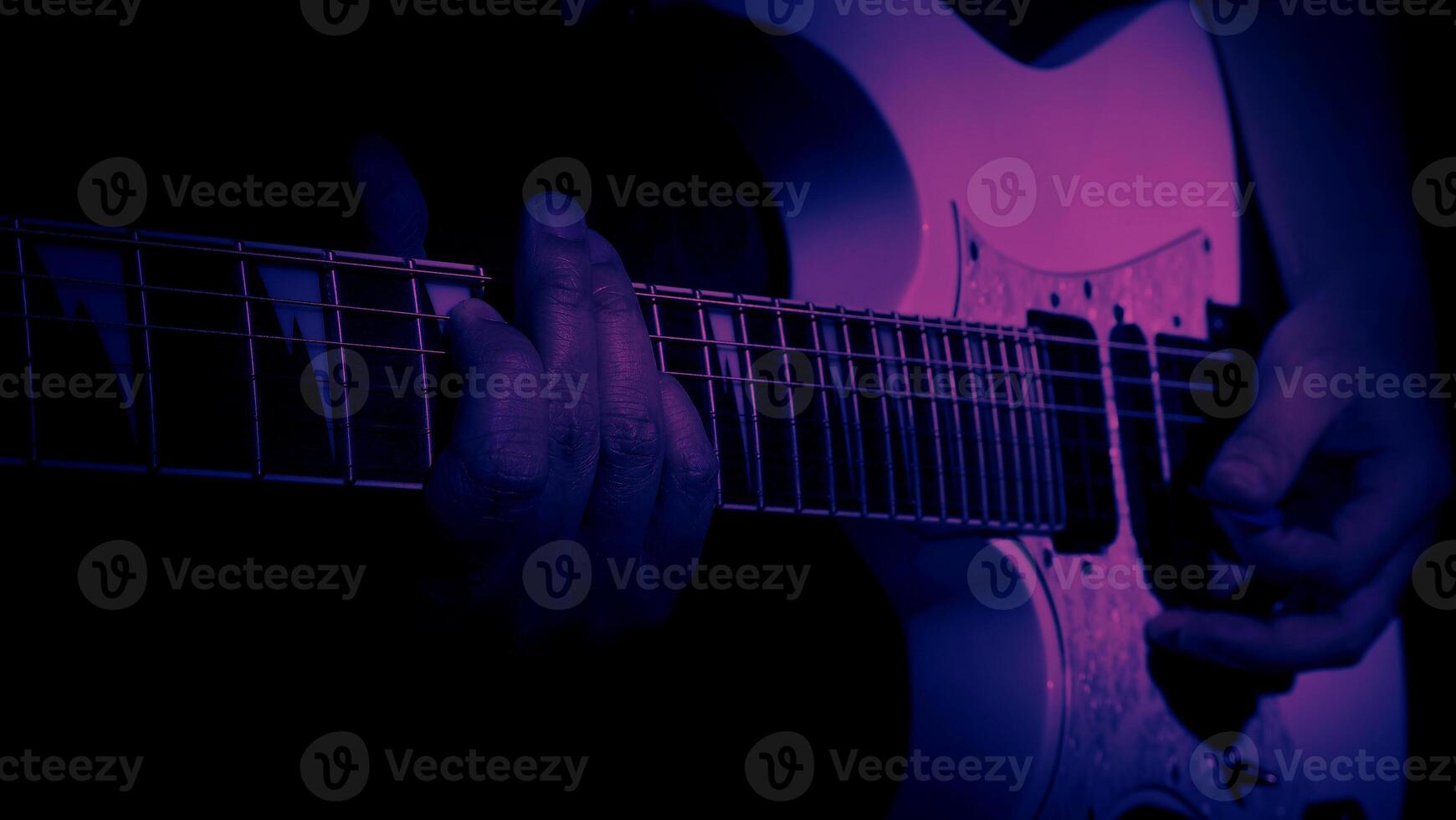 Guitarist Playing Guitar In Studio. Low key of man hand play white electric guitar for songs and cover music or skill practice. Close up of musician playing guitars instrument against black background photo