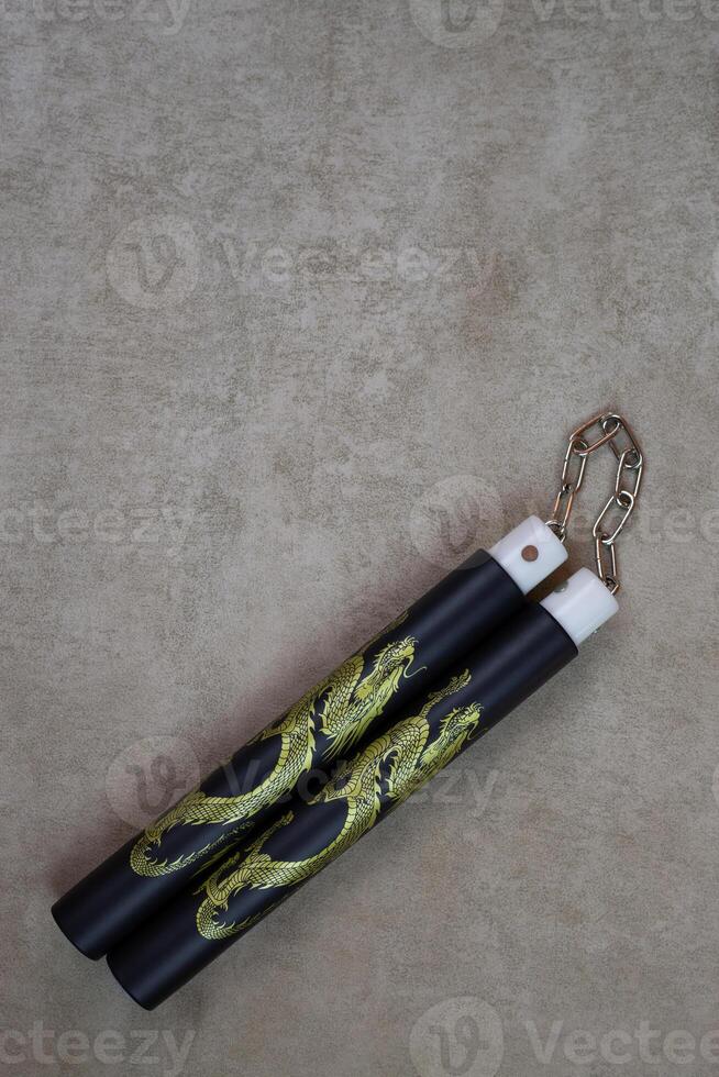 Vertical photography of training nunchucks for self training in use of melee weapons on light background, traditional oriental edged weapons of impact and strangulation type photo