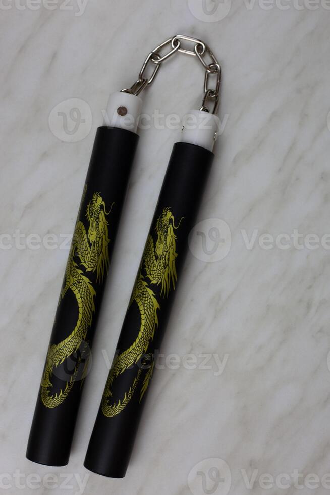 Eastern melee weapons, training nunchucks for learning strikes and improving body dexterity at home, unusual edged weapons on a white table, vertical photo
