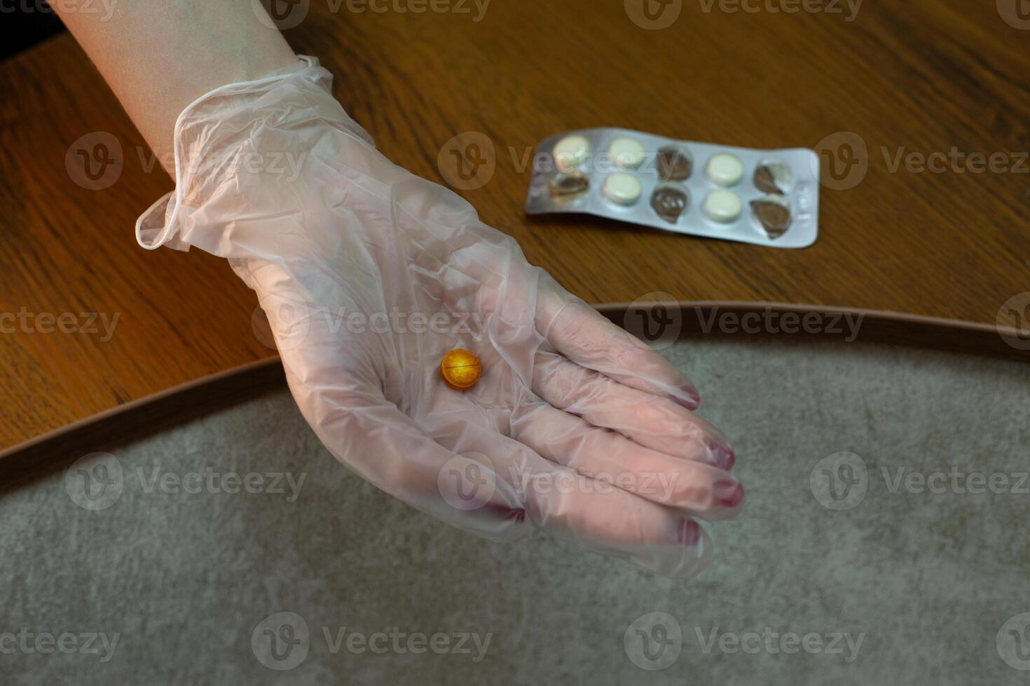 Hand in medical glove holds expired tablet brown color against background of plate of tablets that have lost their expiration date, monitoring suitability and freshness of medicaments photo